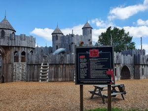 A photo of the Dragon Castle at Knockhatch. It is a wooden castle with lots of slides, stairs, rock climbing areas and entraces.